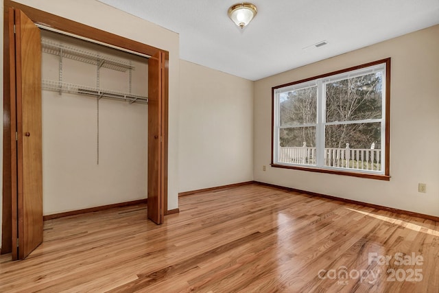 unfurnished bedroom with light wood finished floors, visible vents, baseboards, and a closet