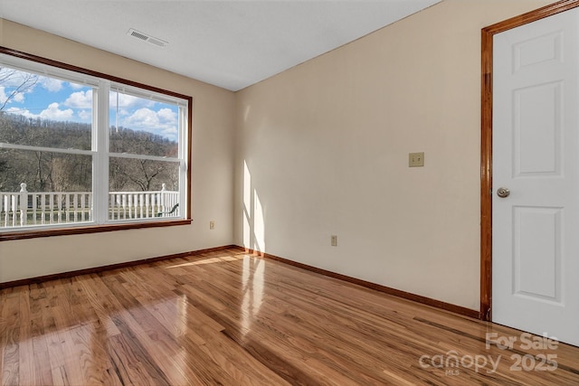 empty room with visible vents, baseboards, and light wood finished floors