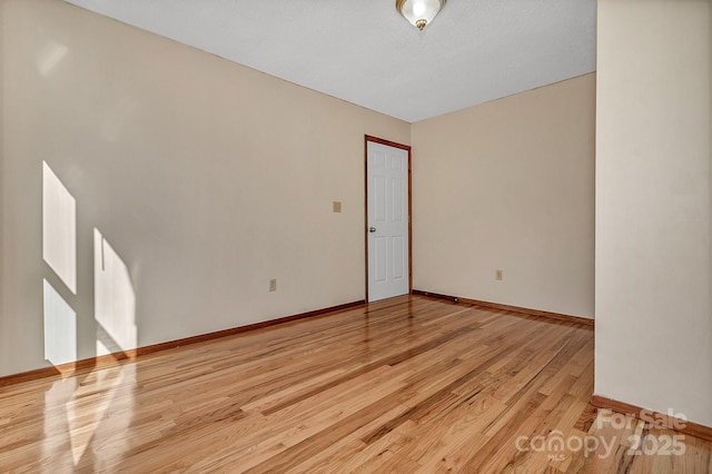 spare room featuring baseboards and light wood-type flooring