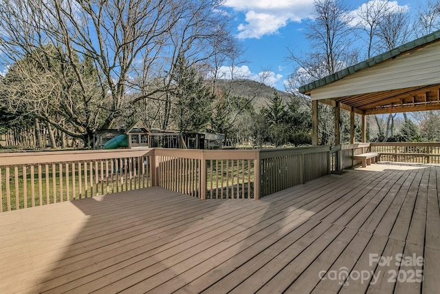 wooden deck featuring a mountain view and a playground