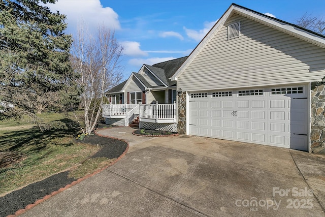 single story home with concrete driveway, stone siding, an attached garage, and covered porch