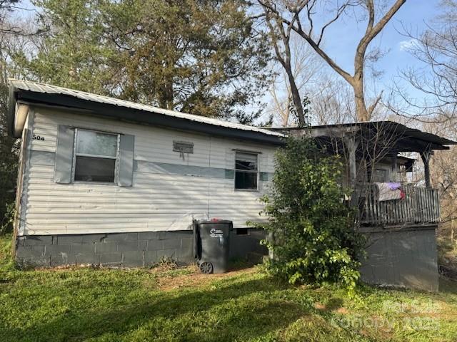 view of side of home featuring crawl space, a lawn, and metal roof