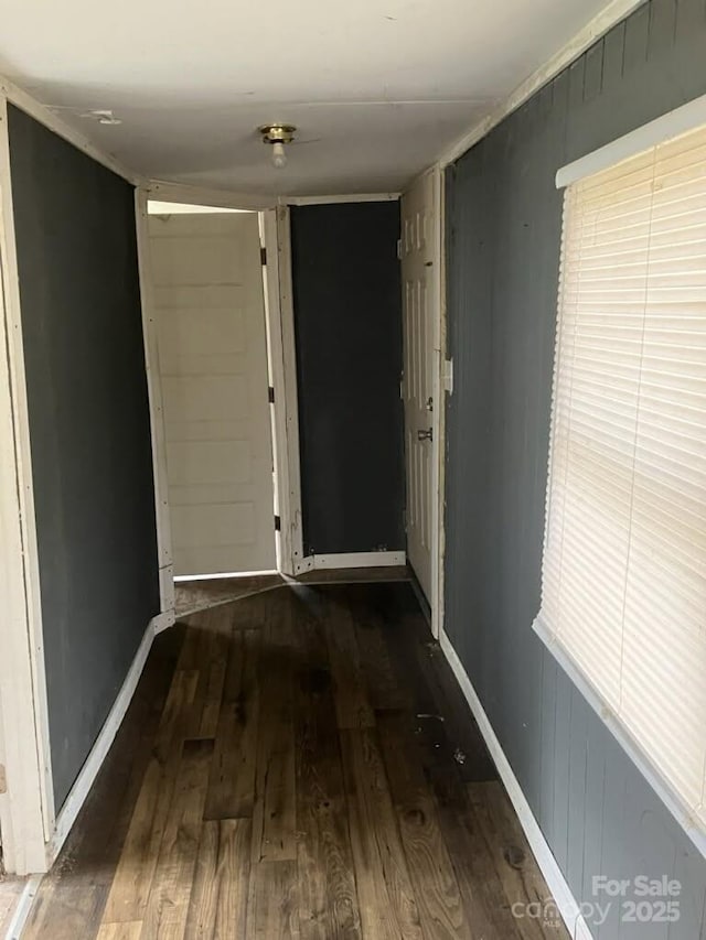 corridor with baseboards and wood finished floors