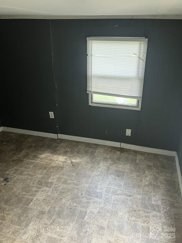 spare room featuring brick patterned floor and baseboards