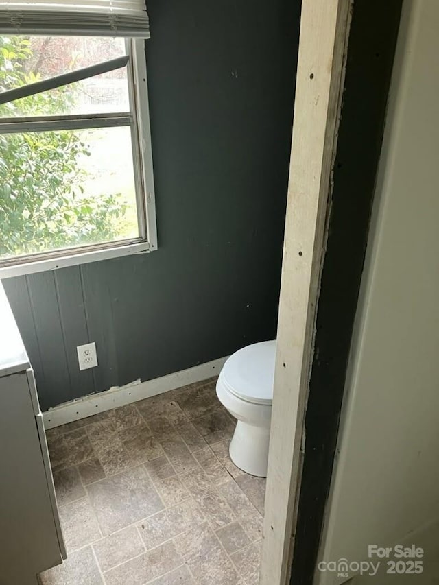 bathroom featuring vanity, stone finish floor, toilet, and baseboards