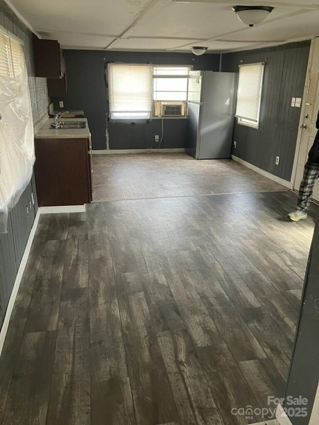 interior space with a sink, cooling unit, baseboards, and dark wood-style flooring