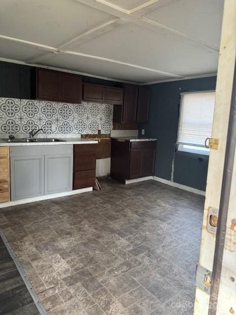 kitchen featuring tasteful backsplash, light countertops, and a sink