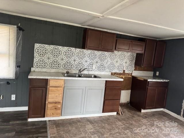 kitchen featuring light countertops, baseboards, and a sink