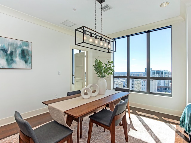 dining room with wood finished floors, visible vents, baseboards, ornamental molding, and a view of city