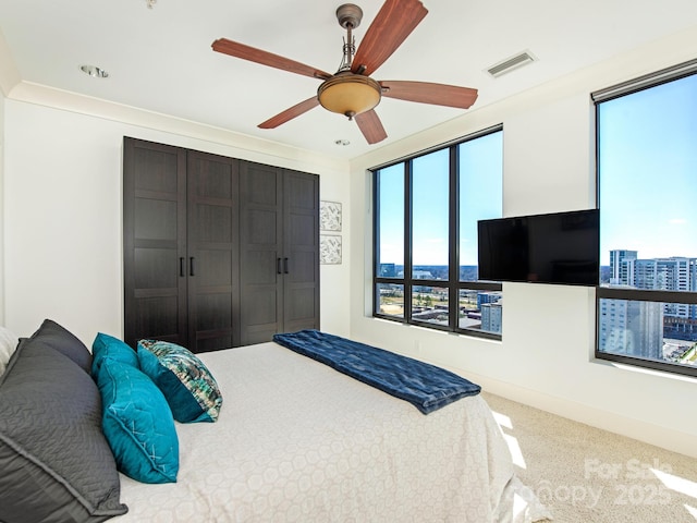 carpeted bedroom featuring a closet, visible vents, baseboards, and ceiling fan