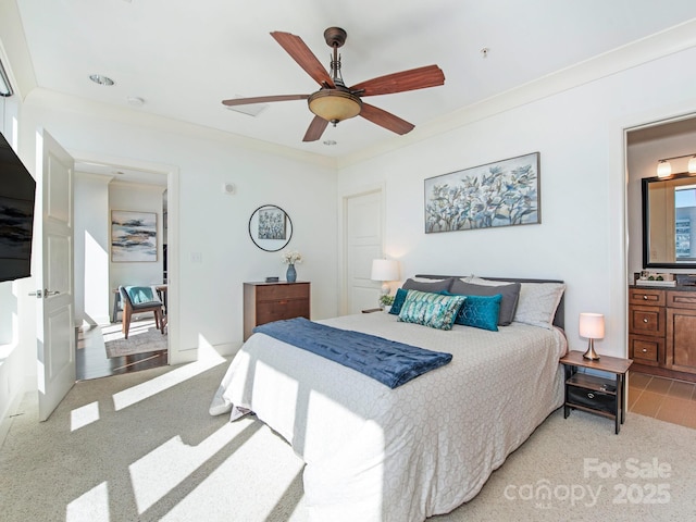 bedroom featuring light carpet, connected bathroom, ceiling fan, and ornamental molding