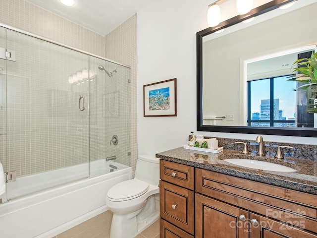 bathroom with tile patterned flooring, a city view, toilet, enclosed tub / shower combo, and vanity