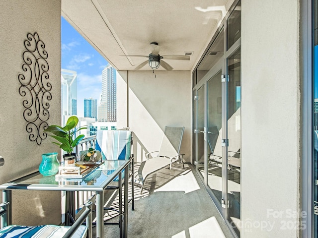 balcony featuring a city view, visible vents, and ceiling fan