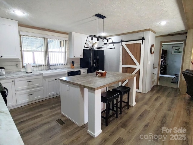 kitchen featuring black appliances, white cabinets, a barn door, and dark wood-style floors