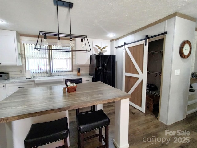 kitchen with light wood-style flooring, a sink, white cabinetry, a barn door, and a kitchen breakfast bar