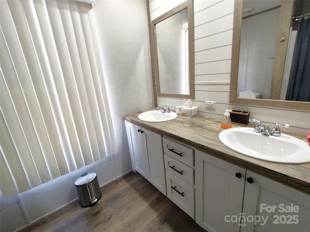 full bathroom featuring double vanity, wood finished floors, a shower with curtain, and a sink