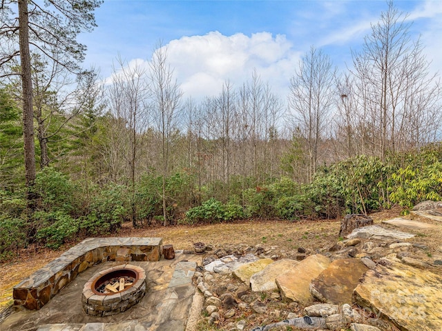 view of yard with a fire pit and a view of trees