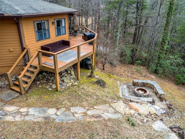 view of yard with an outdoor fire pit, a forest view, and a wooden deck