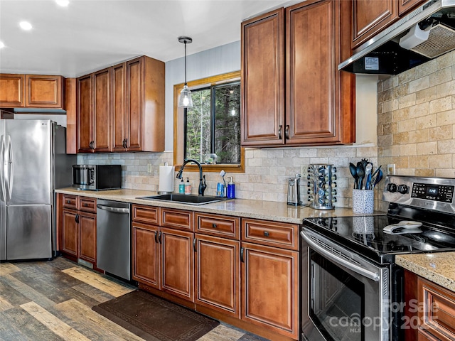 kitchen featuring tasteful backsplash, dark wood-type flooring, under cabinet range hood, stainless steel appliances, and a sink