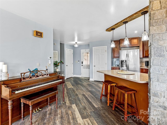 kitchen featuring a kitchen bar, brown cabinets, pendant lighting, stainless steel refrigerator with ice dispenser, and dark wood finished floors