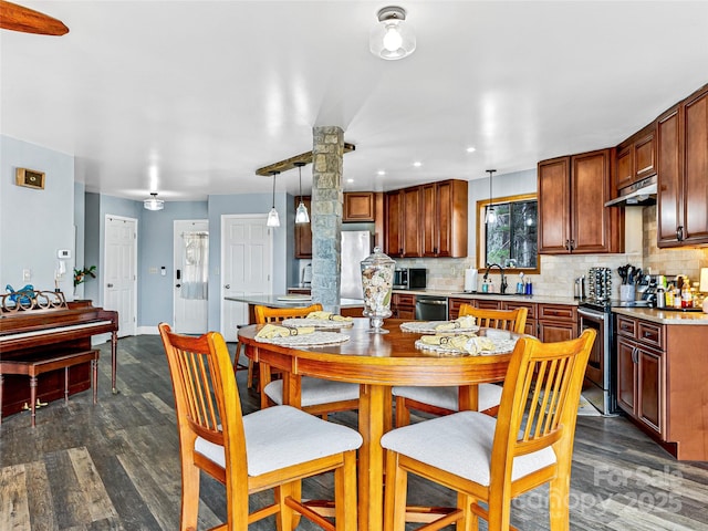 dining area with dark wood finished floors, baseboards, and ornate columns