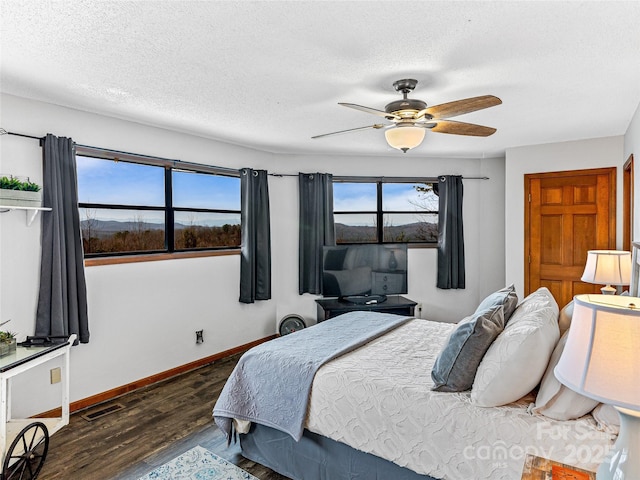 bedroom featuring visible vents, baseboards, dark wood finished floors, ceiling fan, and a textured ceiling