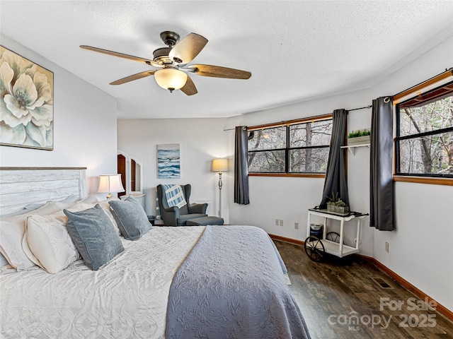 bedroom featuring a textured ceiling, dark wood finished floors, arched walkways, baseboards, and ceiling fan