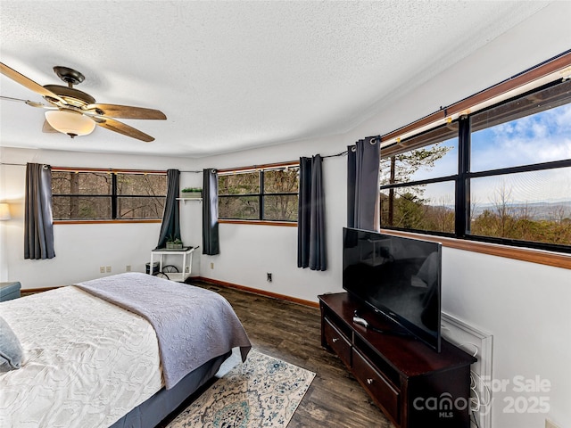 bedroom featuring dark wood finished floors, ceiling fan, baseboards, and a textured ceiling