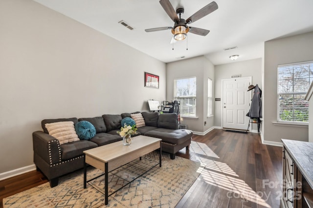 living room featuring a ceiling fan, visible vents, dark wood-style flooring, and baseboards