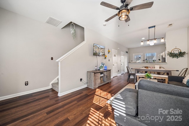 living room with visible vents, baseboards, wood finished floors, and stairway