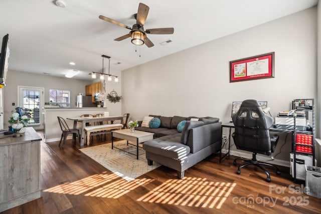 living area with visible vents, baseboards, wood finished floors, and a ceiling fan