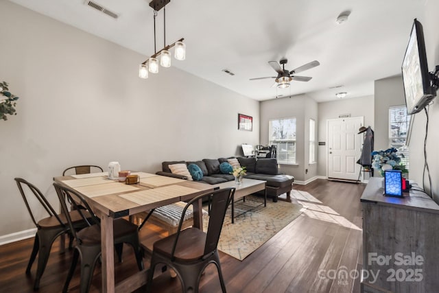 dining area with dark wood finished floors, visible vents, baseboards, and a ceiling fan