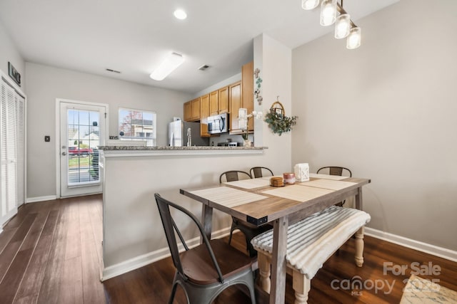 dining room with dark wood-type flooring, visible vents, and baseboards