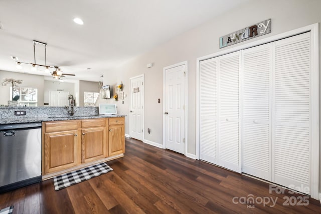 kitchen featuring dark wood-type flooring, ceiling fan, light stone counters, stainless steel dishwasher, and a sink