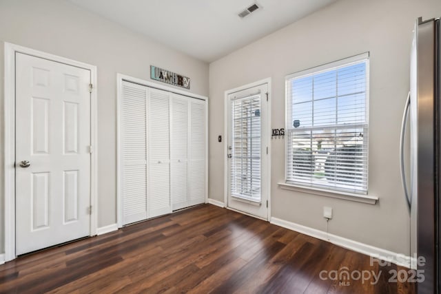 unfurnished bedroom with visible vents, access to outside, freestanding refrigerator, baseboards, and dark wood-style flooring