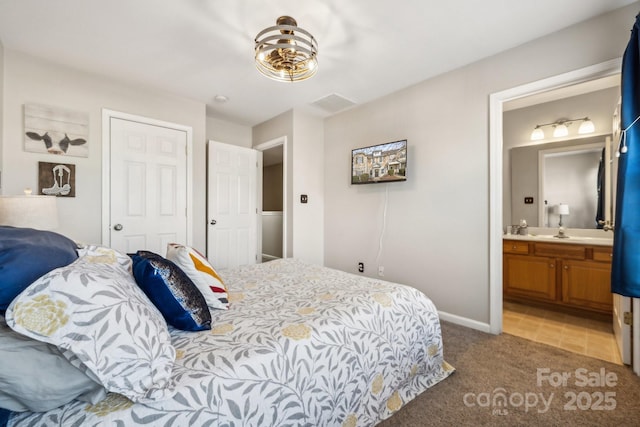 carpeted bedroom featuring a closet, baseboards, and ensuite bathroom