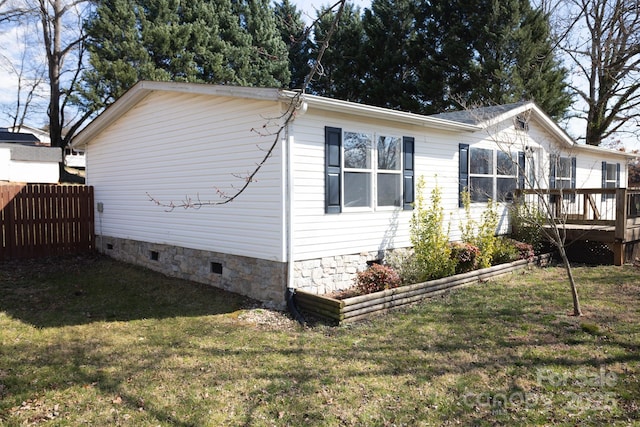 view of side of property featuring crawl space, a deck, a yard, and fence