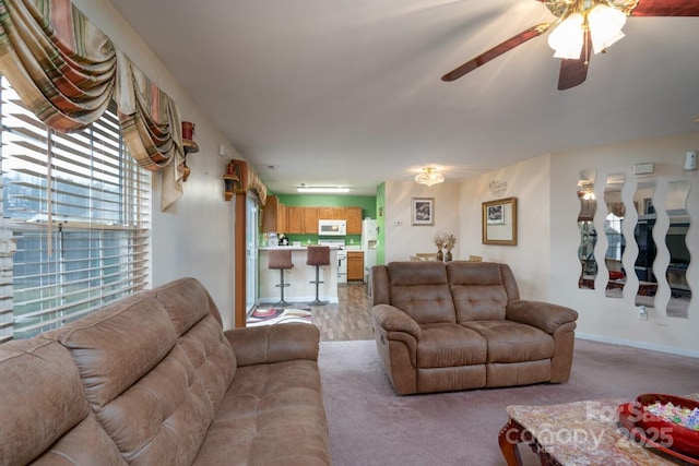 living area featuring a ceiling fan and baseboards