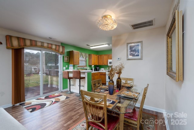 dining space with visible vents, baseboards, and wood finished floors