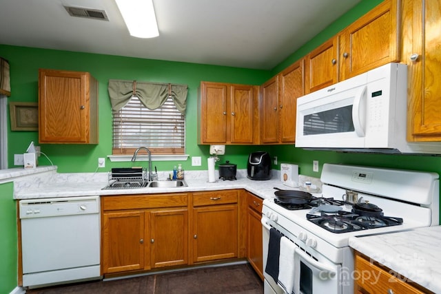 kitchen with white appliances, light countertops, visible vents, and a sink