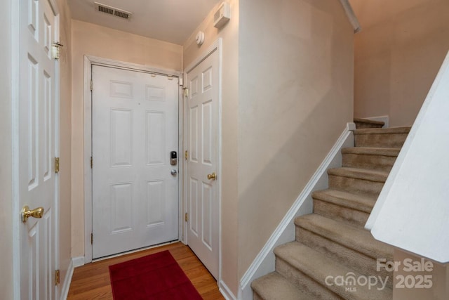 doorway to outside with stairs, wood finished floors, visible vents, and baseboards