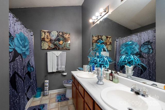 full bath with double vanity, toilet, baseboards, and a sink