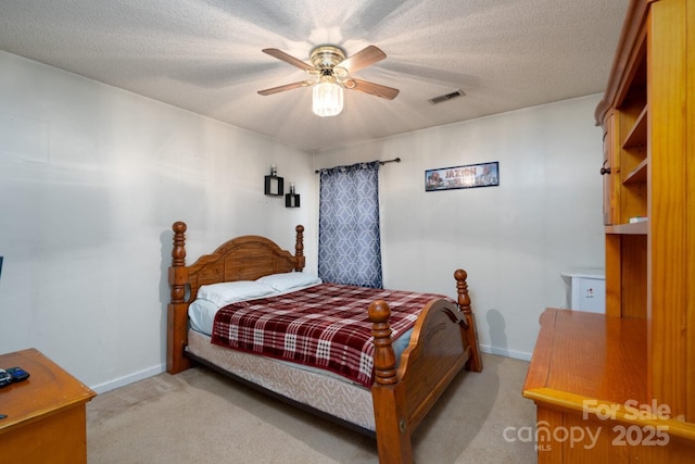 bedroom with a textured ceiling, ceiling fan, visible vents, and light carpet