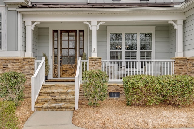 view of exterior entry with crawl space, stone siding, and covered porch