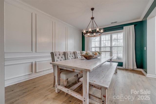 dining room with crown molding, a decorative wall, visible vents, and breakfast area