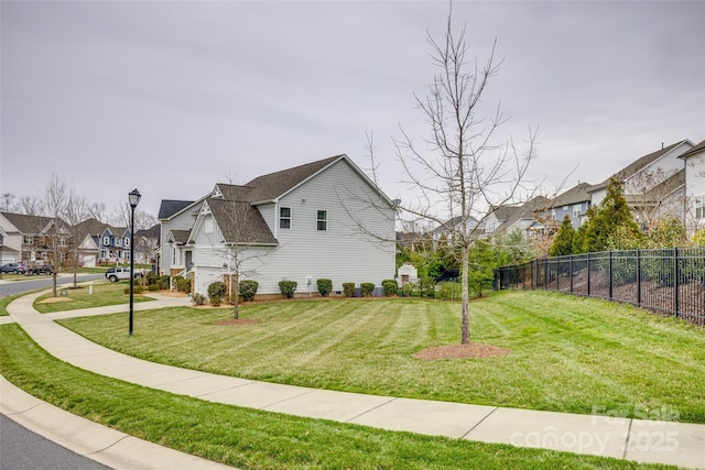 view of side of property featuring a residential view, a lawn, roof with shingles, and fence