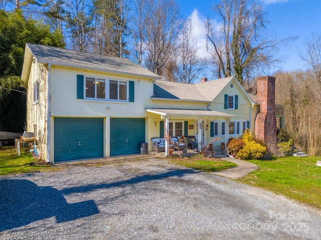 view of front of home with a front lawn, a porch, stucco siding, a chimney, and driveway