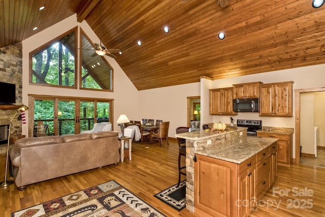 kitchen with electric range, a stone fireplace, open floor plan, and black microwave