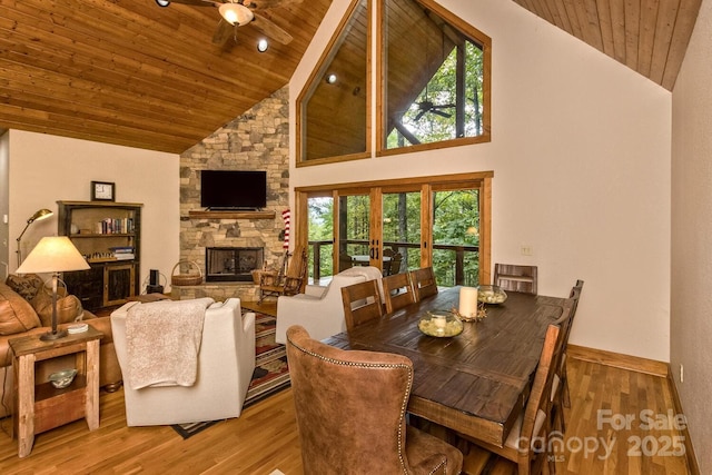 dining space with wood finished floors, high vaulted ceiling, wooden ceiling, and a fireplace