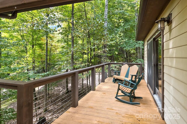 wooden terrace featuring a view of trees